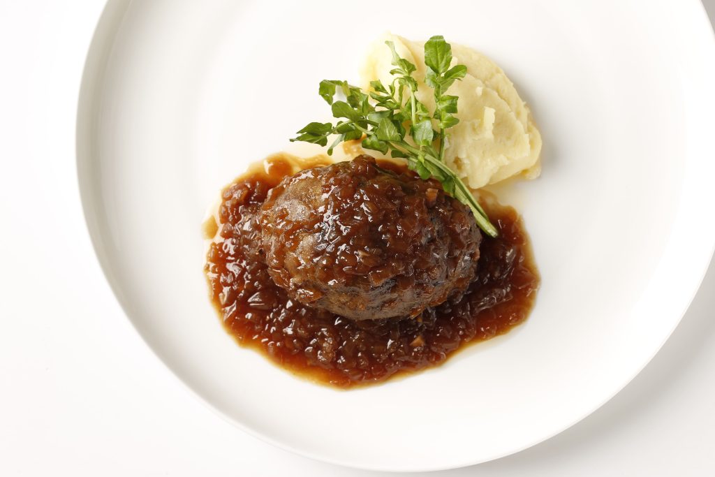 奥出雲和牛のハンバーグが玉ねぎソースとマッシュポテトと白い皿に盛り付けられた様子
