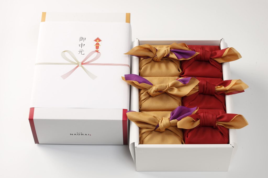 奥出雲NAORAIのお中元ギフトの熨斗がかけられたギフトボックスと、風呂敷に丁寧に包まれたキューブ米6つの詰め合わせギフト